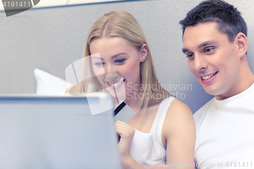 Image of couple in bed with laptop computer and credit card