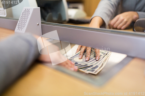 Image of clerk giving cash money to customer at bank office