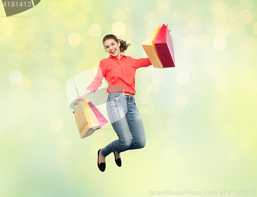 Image of smiling young woman with shopping bags jumping