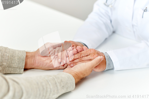 Image of close up of doctor holding old man hand