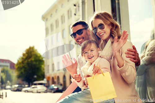 Image of happy family with child and shopping bags in city