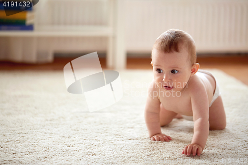 Image of little baby in diaper crawling on floor at home