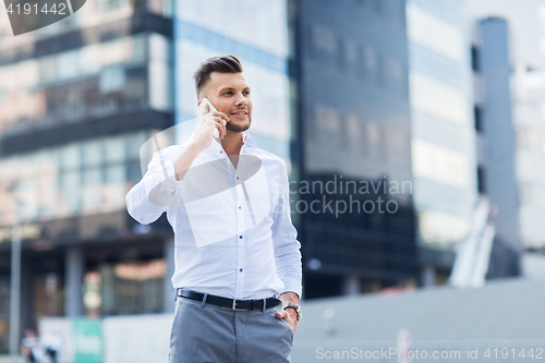 Image of happy man with smartphone calling on city street