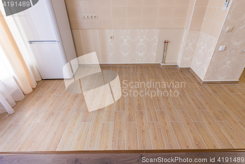 Image of Zoning floor in the interior, ceramic kitchen tiles bordered with laminate flooring in the living room