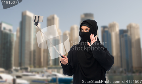 Image of muslim woman in hijab taking selfie by smartphone