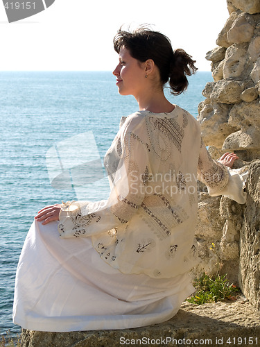 Image of Lonely Young Woman on Stone Looking to Sea