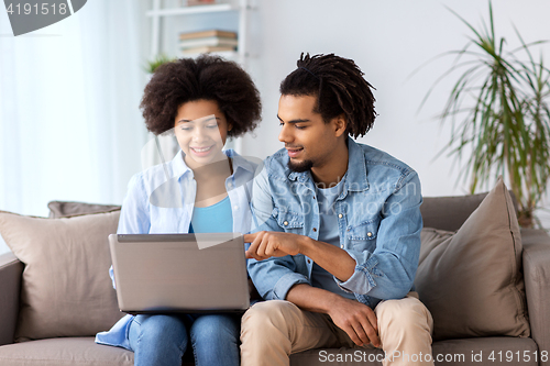 Image of smiling happy couple with laptop at home