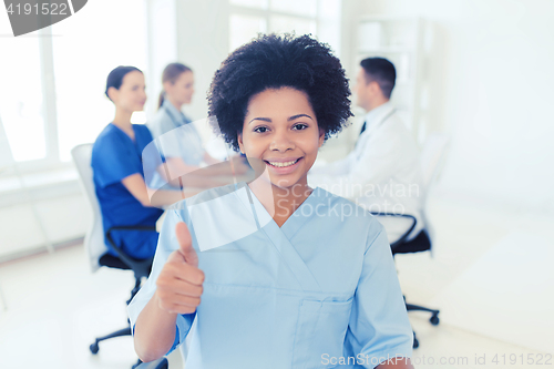 Image of happy female doctor or nurse showing thumbs up