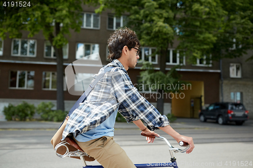 Image of young hipster man with bag riding fixed gear bike