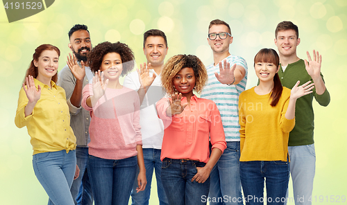 Image of international group of happy people waving hand