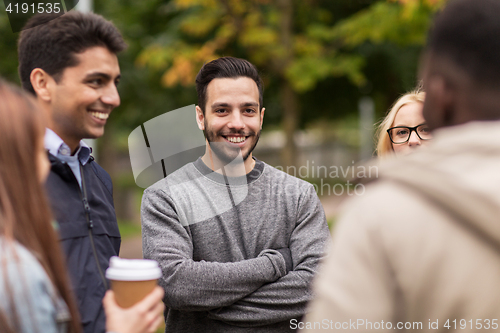 Image of happy friends walking along autumn park