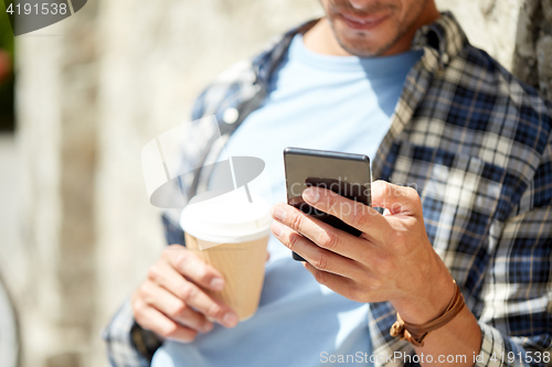 Image of man with smartphone and coffee on city street