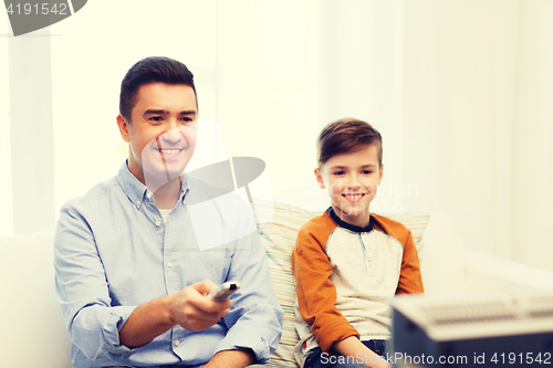 Image of smiling father and son watching tv at home