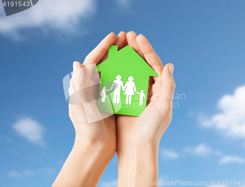 Image of hands holding green house with family pictogram