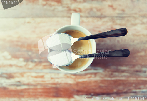 Image of close up of white sugar on teaspoon and coffee cup