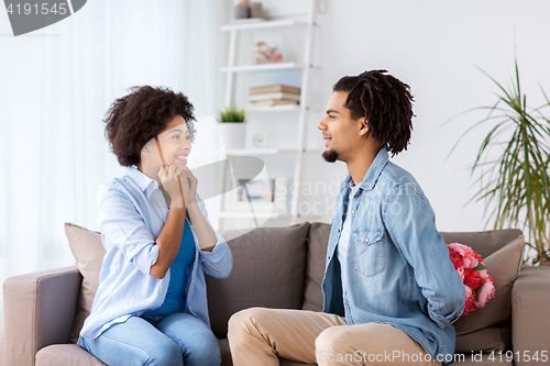 Image of happy couple with bunch of flowers at home
