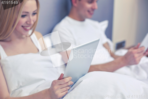 Image of smiling couple in bed with tablet pc computers