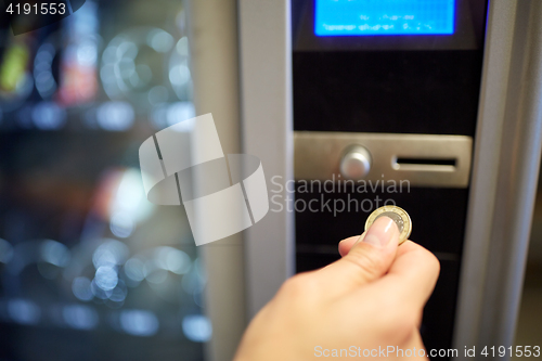 Image of hand inserting euro coin to vending machine slot