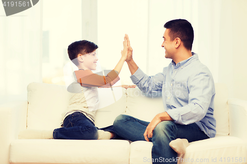 Image of happy father and son doing high five at home