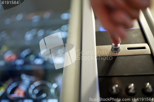 Image of hand pushing button on vending machine