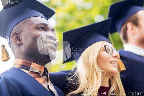 Image of happy students or bachelors in mortar boards