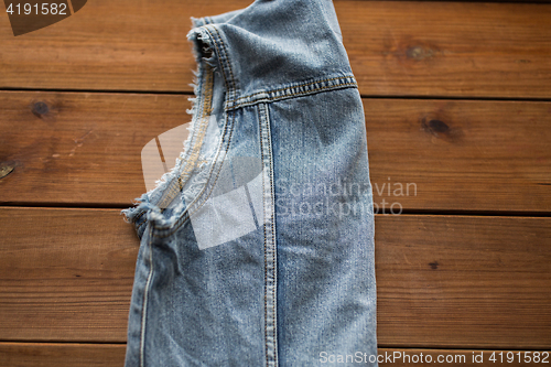 Image of close up of denim vest or waistcoat on wood