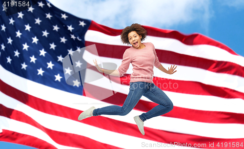 Image of happy african woman jumping over american flag