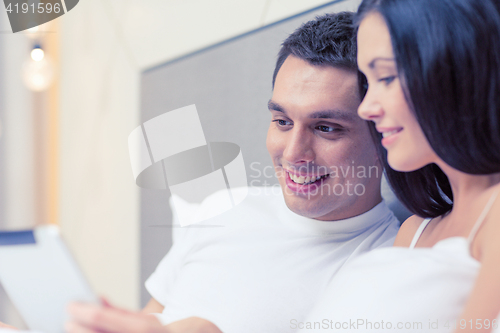 Image of smiling couple in bed with tablet pc computers