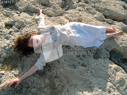 Image of Young barefoot lady on stone beach