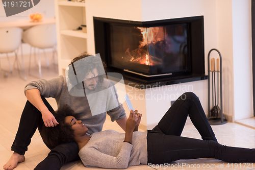 Image of multiethnic couple used tablet computer on the floor