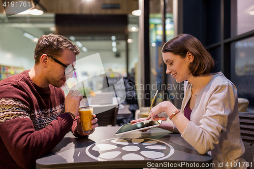 Image of happy couple with tablet pc and smoothie at cafe