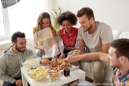 Image of happy friends with drinks eating pizza at home