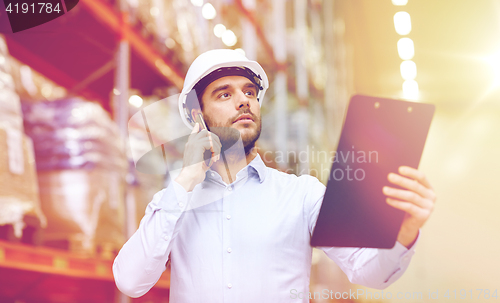 Image of man with clipboard and smartphone at warehouse