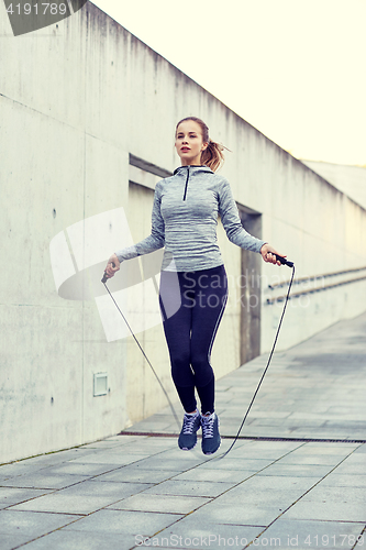 Image of woman exercising with jump-rope outdoors