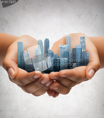 Image of hands holding city over gray concrete background
