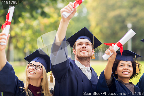 Image of happy students in mortar boards with diplomas