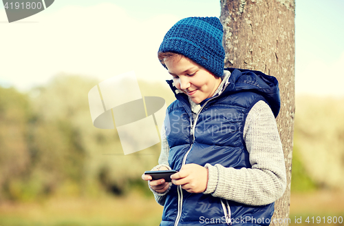 Image of happy boy playing game on smartphone outdoors