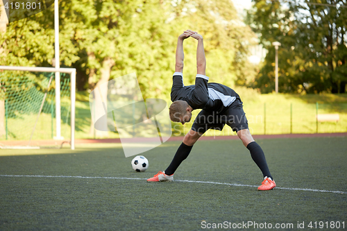 Image of soccer player stretching leg on field football