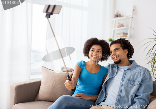 Image of happy couple with smartphone taking selfie at home