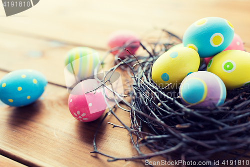 Image of close up of colored easter eggs in nest on wood