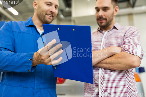 Image of auto mechanic with clipboard and man at car shop