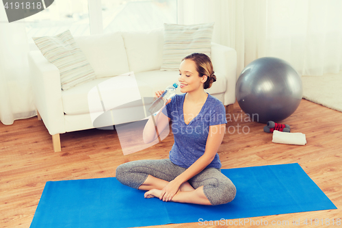 Image of happy woman with water bottle exercising at home