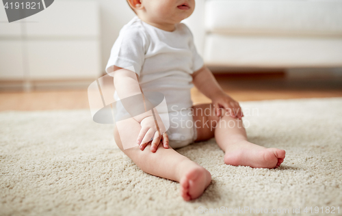 Image of happy baby boy or girl sitting on floor at home