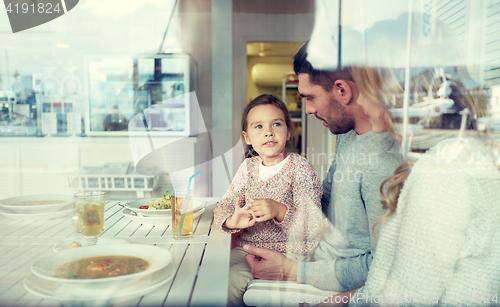 Image of happy family having dinner at restaurant or cafe