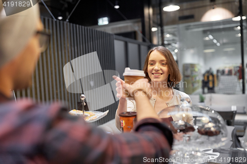 Image of seller giving coffee cup to woman customer at cafe