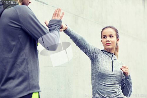 Image of woman with coach working out strike outdoors