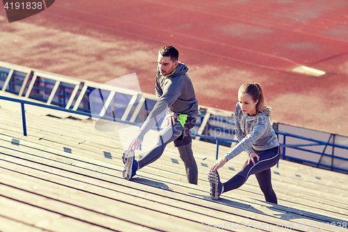 Image of couple stretching leg on stands of stadium