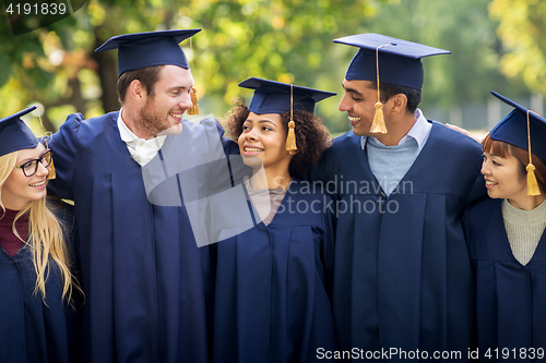 Image of happy students or bachelors in mortar boards