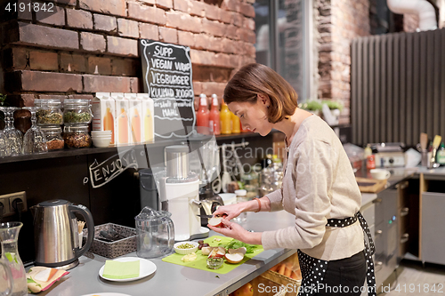Image of happy woman or barmaid cooking at vegan cafe