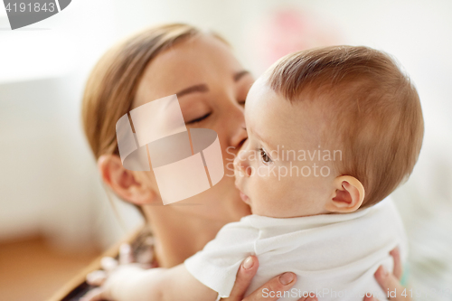 Image of happy young mother kissing little baby at home